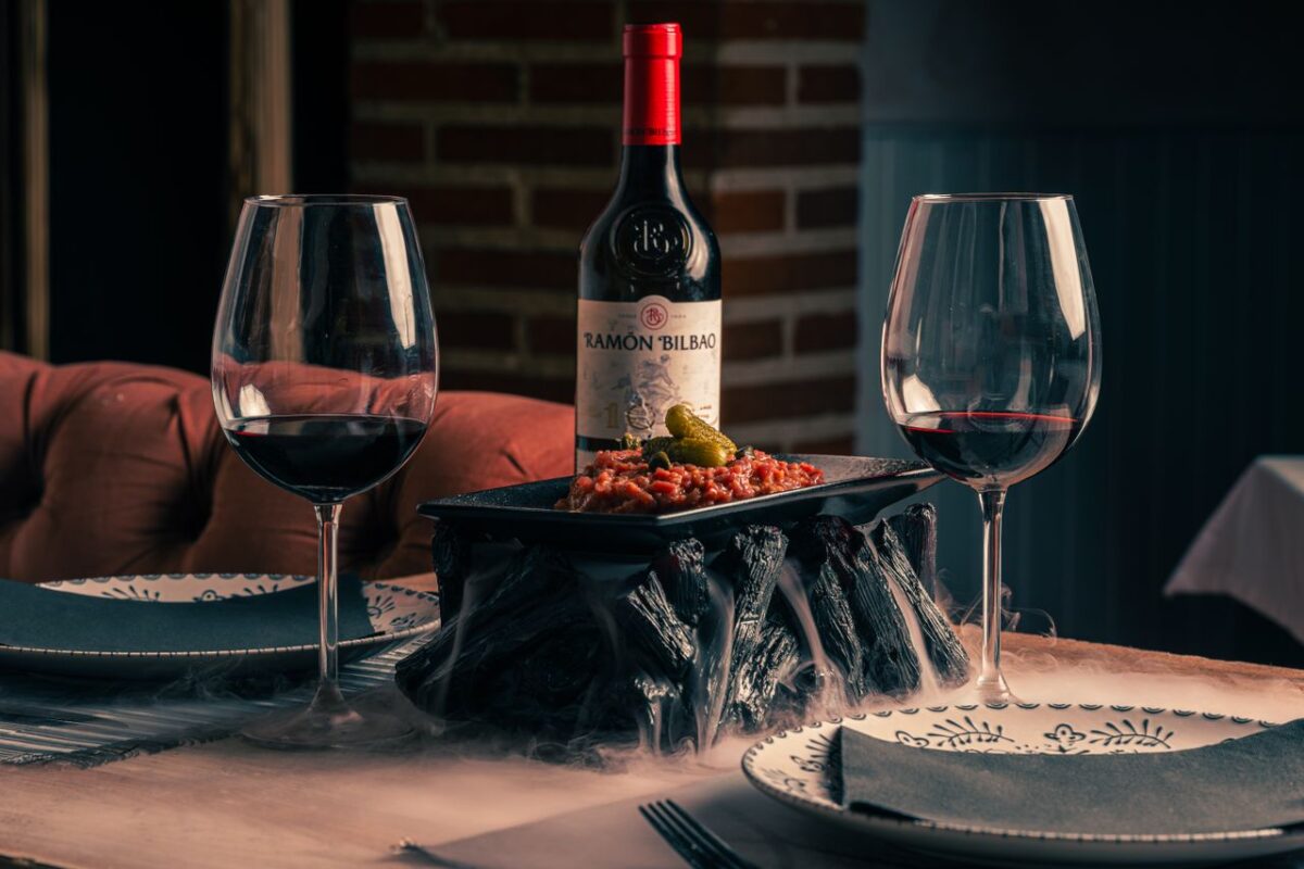 room-01 Cozy dining table with red wine, appetizers, and stylish dinnerware, perfect for a romantic evening.