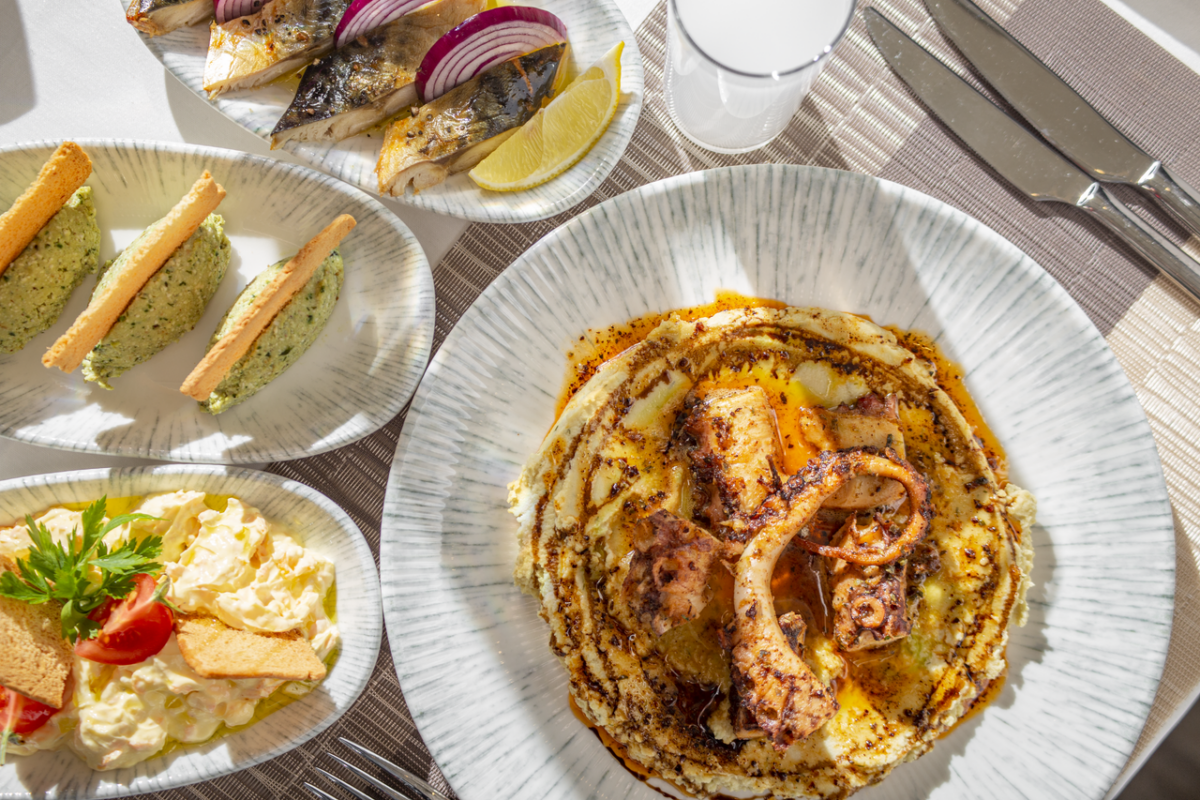 SB Déco Ambiance Delicious fine dining seafood platter featuring grilled octopus and fresh sides served on elegant tableware.