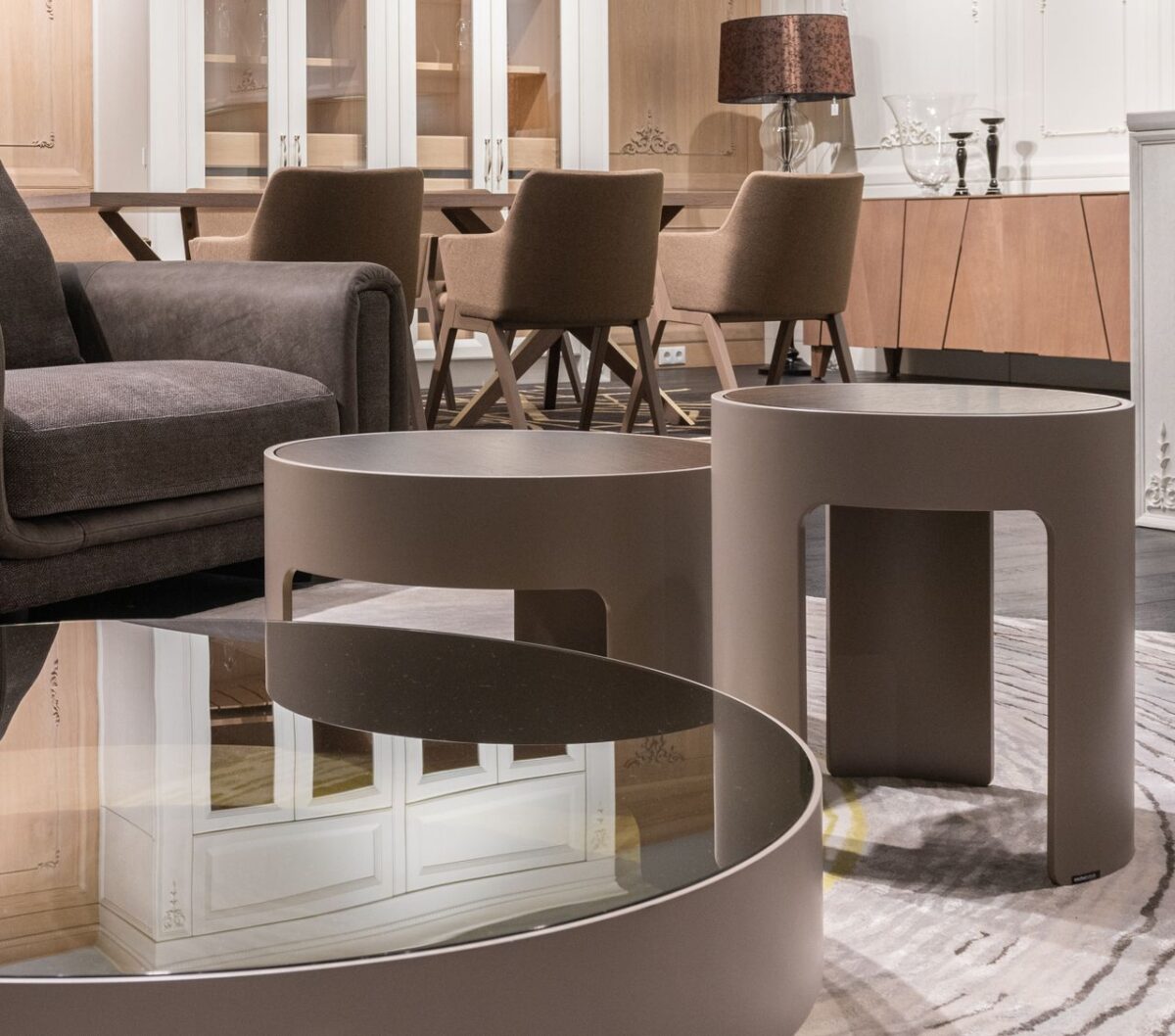 SB Déco Ambiance Small round tables placed near sofa and and sat of brown chairs at wooden cupboard with lamp and candlestick in modern apartment